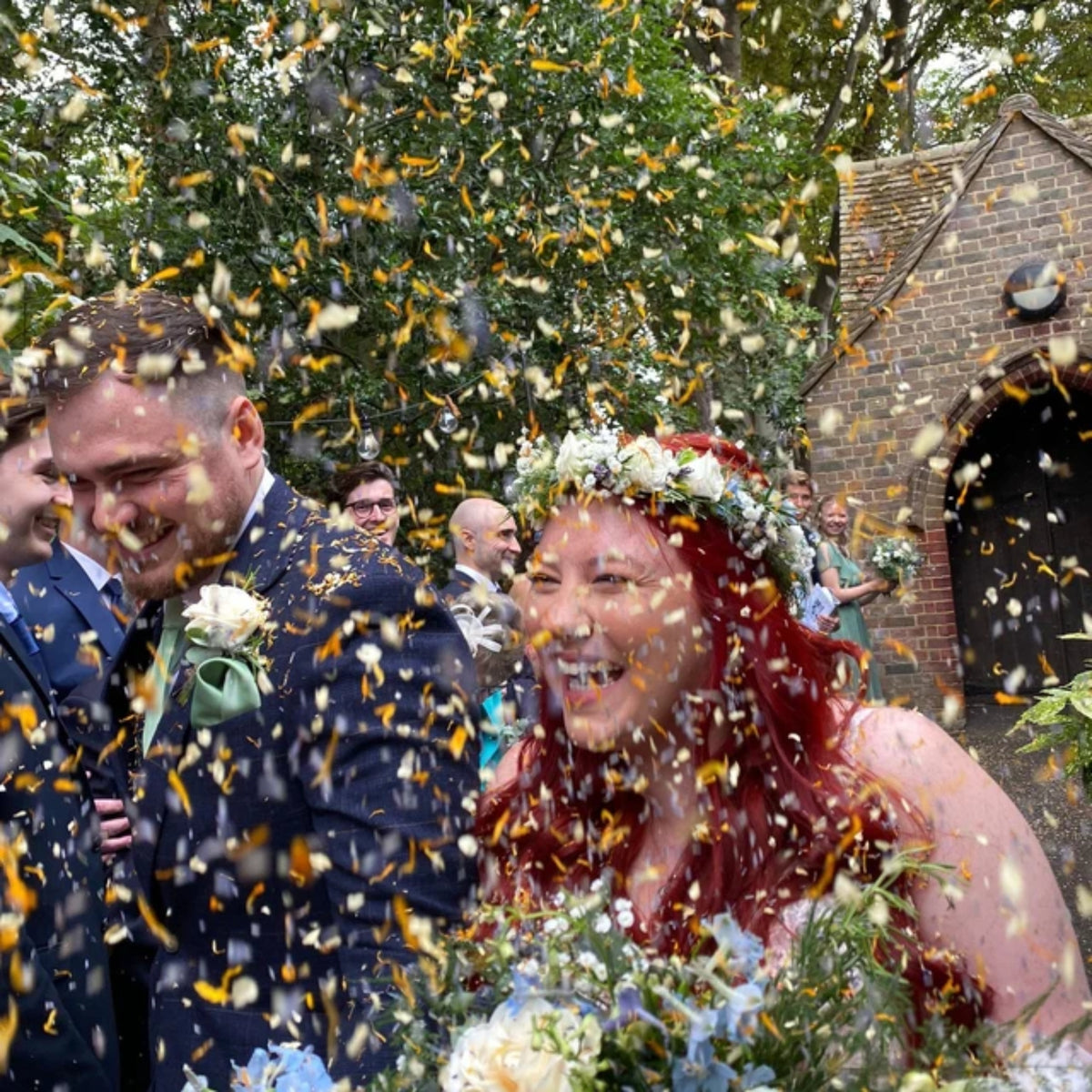 Real wedding confetti photo - Our petals in action - The Dried Petal Company - Wedding couple with confetti, surrounded by guests - The Dried Petal Company - Amber
